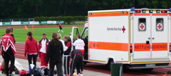 Gemeinsam mit dem Rettungsdienst versorgen die Deisenhofener Rotkreuzler einen Besucher mit Bandscheibenvorfall
